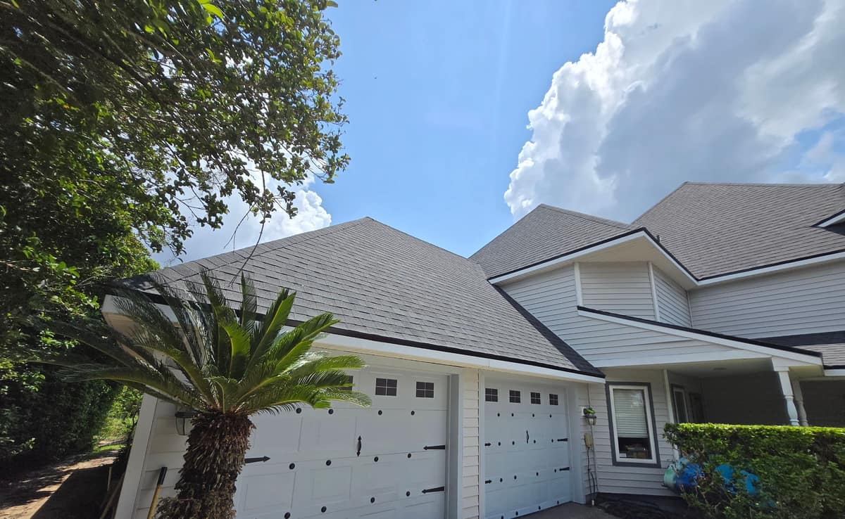 Hip roof over the garage, with cap shingles along the hips and the two-story wing beyond