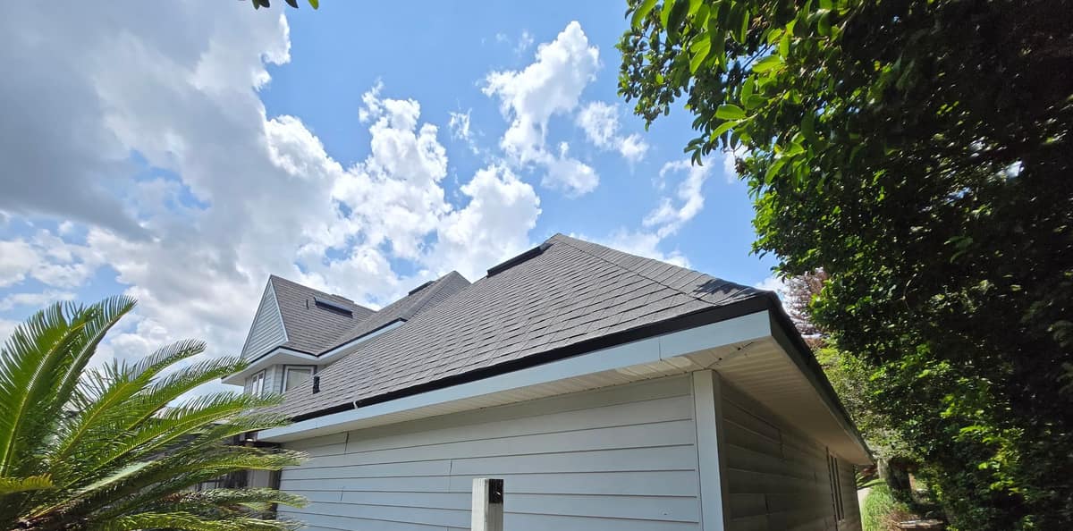 Side wing roof with low black vents near the ridge, a dark eave edge and white fascia