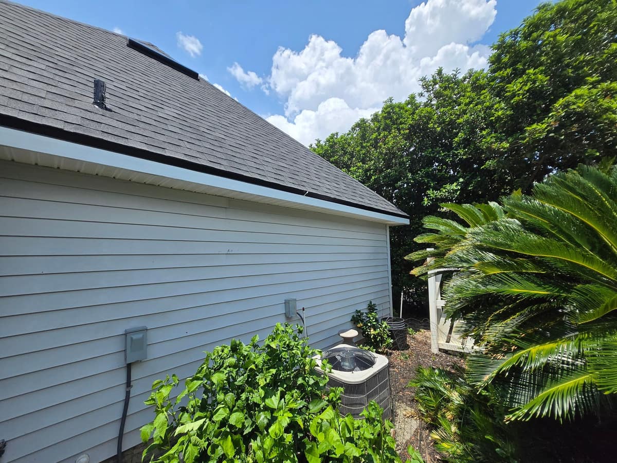 Dark shingles with a black pipe vent and a low roof vent near the ridge above white fascia