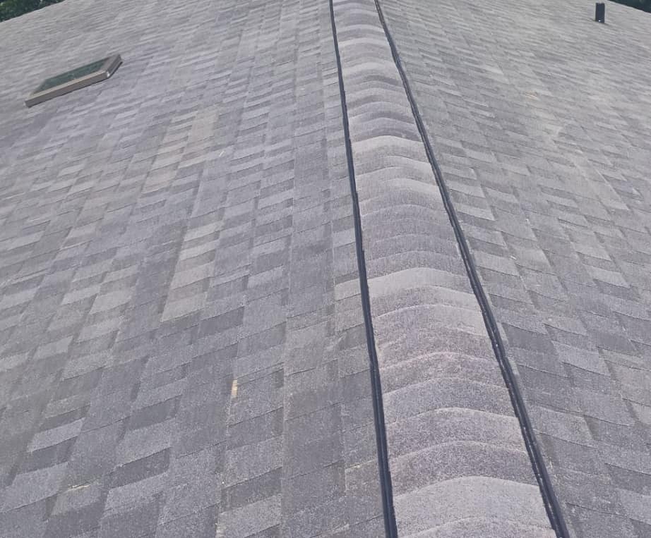 Raised ridge cap shingles over a ridge vent, with a skylight and a pipe vent nearby