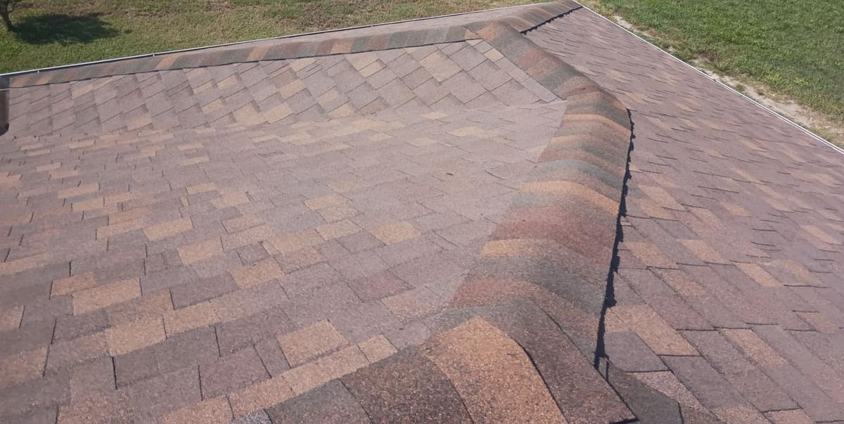 Two capped hip lines meeting above the front lawn on the rose and tan roof