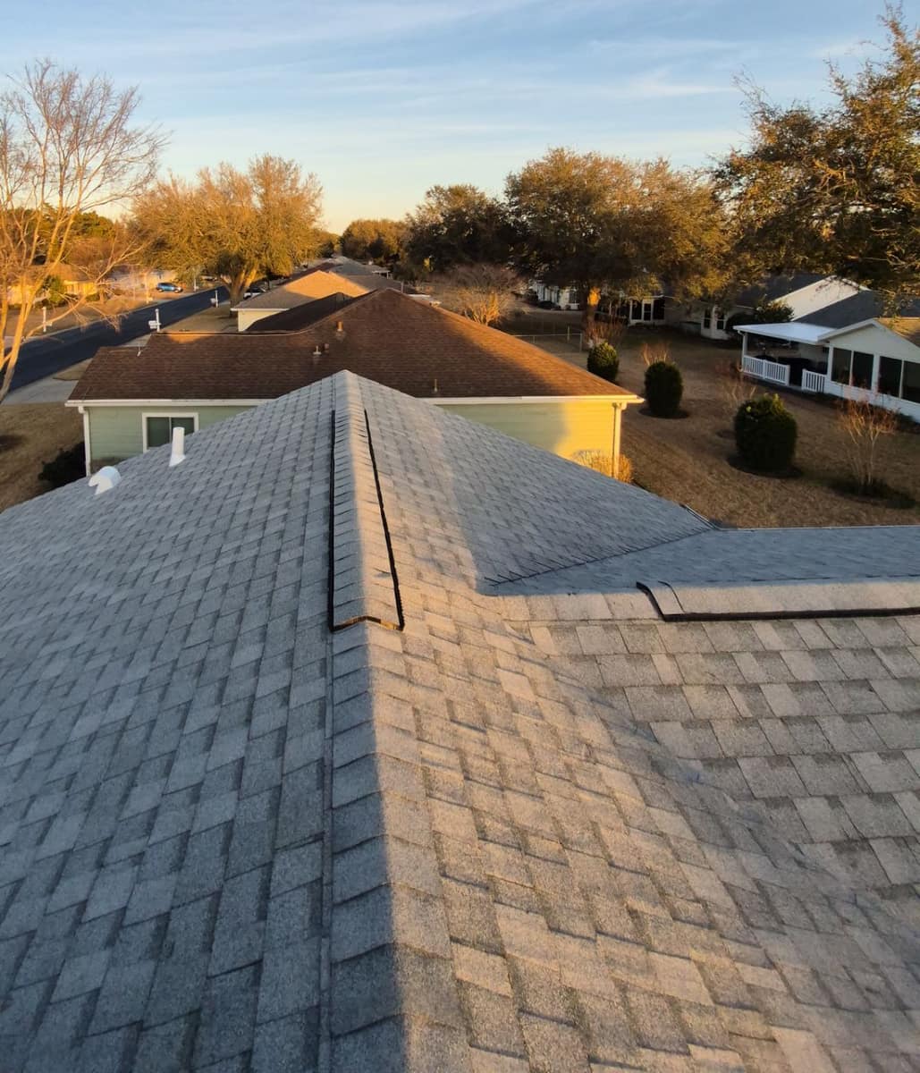 Hip and ridge of the new light gray shingle roof on a one-story Dunnellon home at sunset