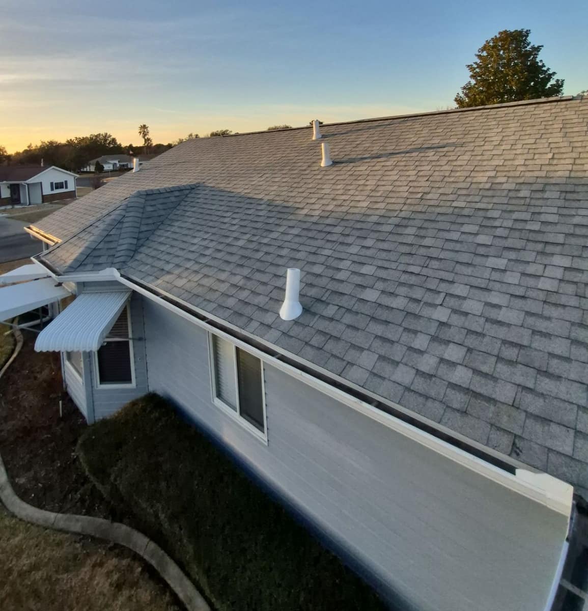 Side of the Dunnellon home with a hip roof, white gutter, window awnings and four white pipe vents