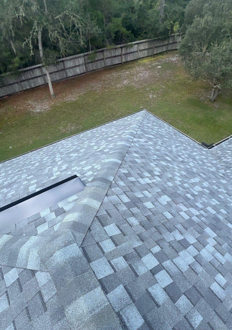 Hip cap and box vent over the back corner of the Eustis roof, above a fence and lawn