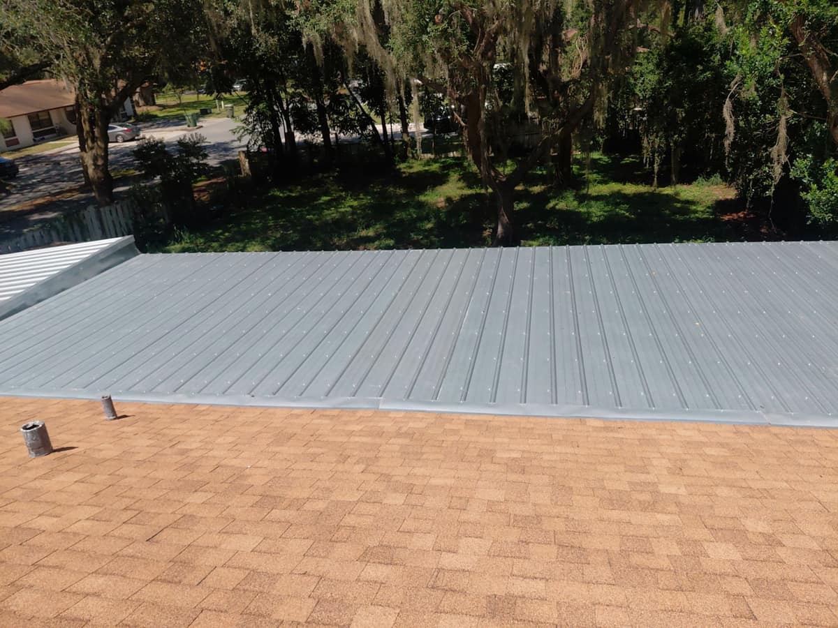 Leesburg home with sandy tan shingles meeting a silver metal low-slope section behind them