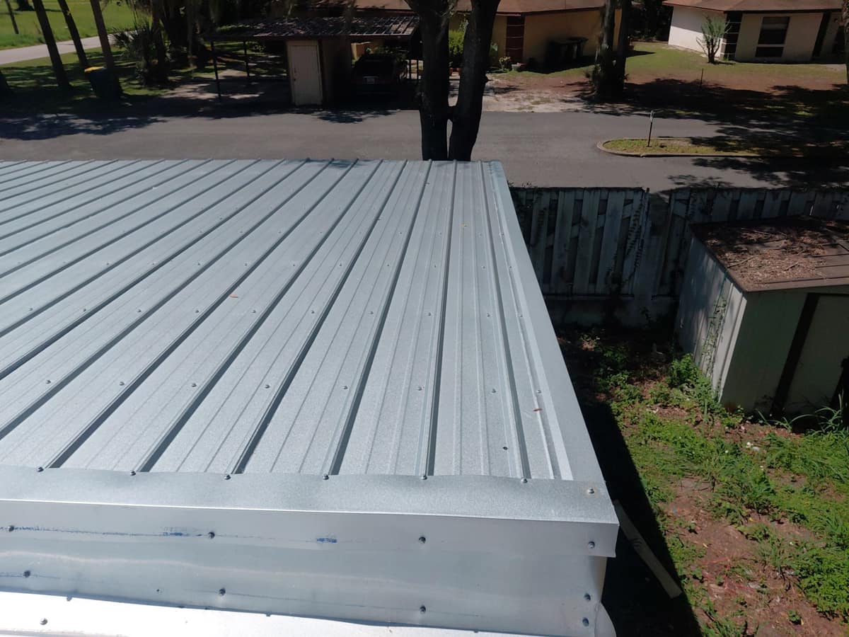 Screwed metal trim wrapping the edge of the new panels above a wood fence