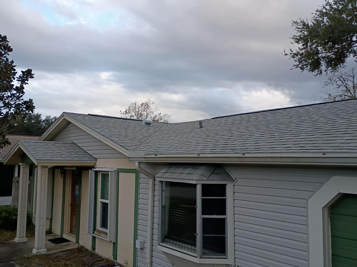 Front of the one-story home with new gray shingles over the gabled porch, main roof and bay window