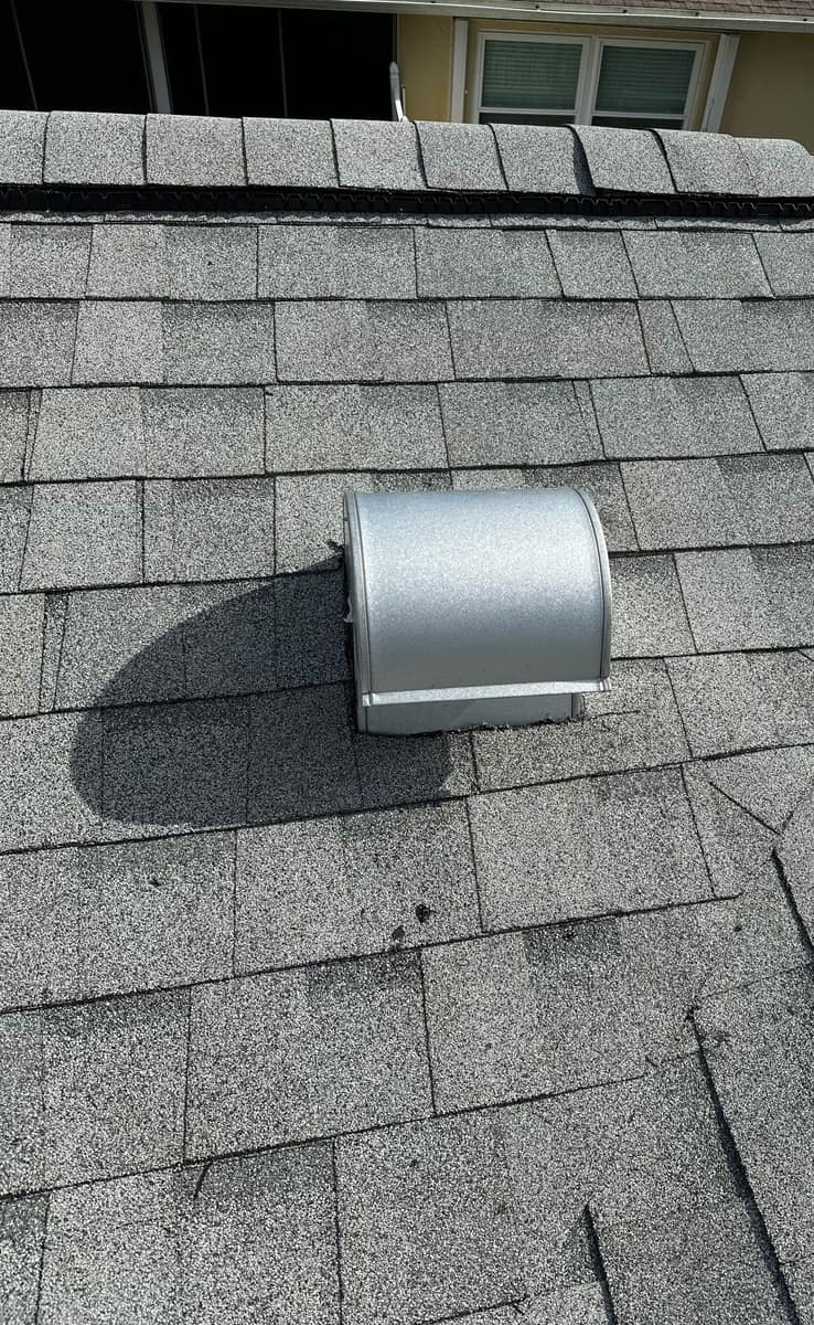 Close view of a metal box vent set in the shingles just below the ridge vent