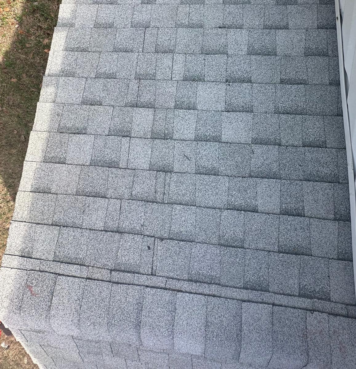 Straight shingle courses on a small low roof beside a wall, seen from above