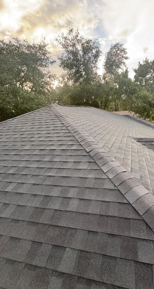 Hip caps climbing toward the ridge under an evening sky, a lower roof section to the right