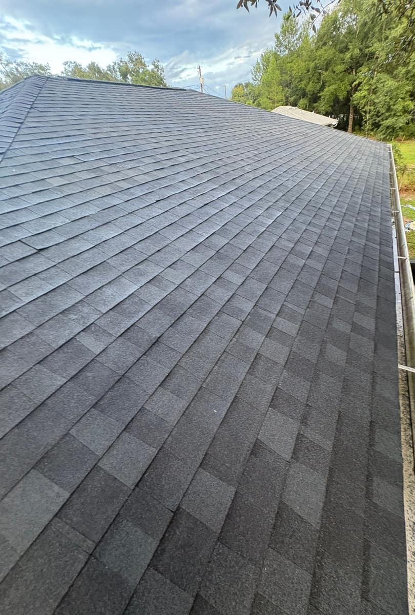 Straight shingle courses running down the back slope, with oak trees along the lot line