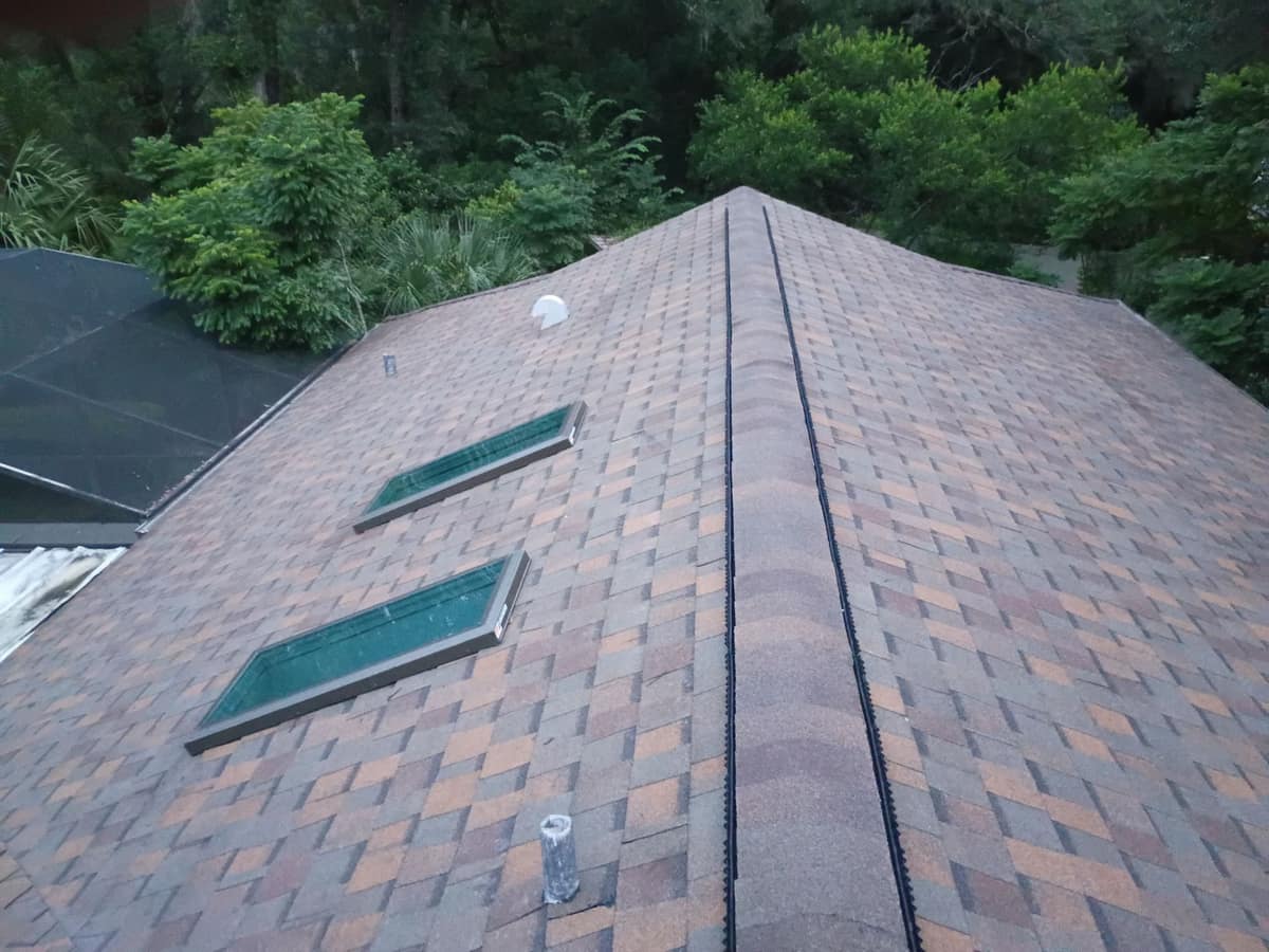 Green-tinted skylights in bronze frames beside the screened pool enclosure at dusk