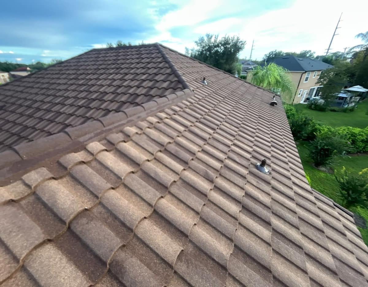 Brown and tan stone-coated metal tile roof on an Orlando home, with pipe vents above the side yard