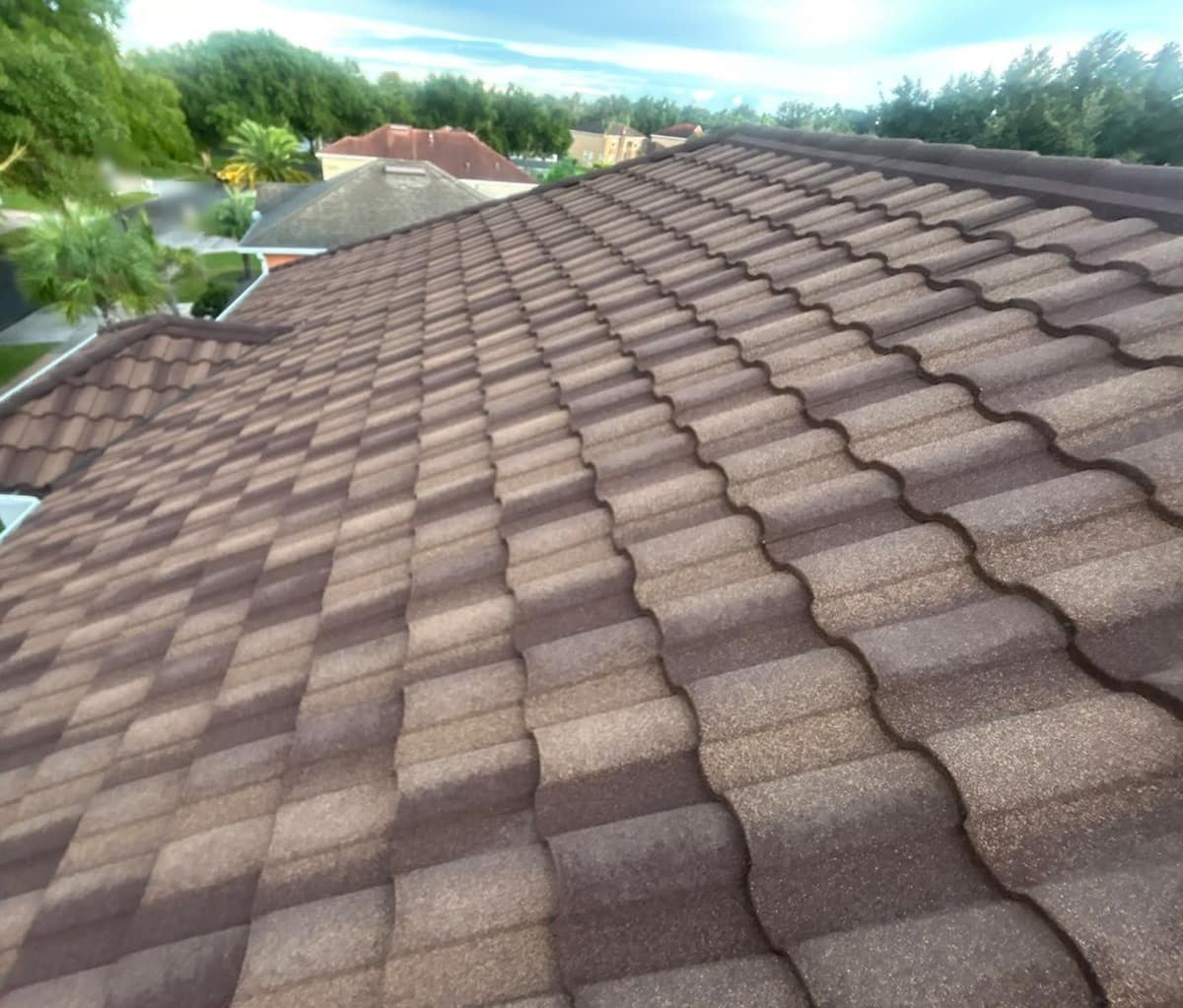 Upper slope of the metal tile roof stepping down to a lower roof section near the street