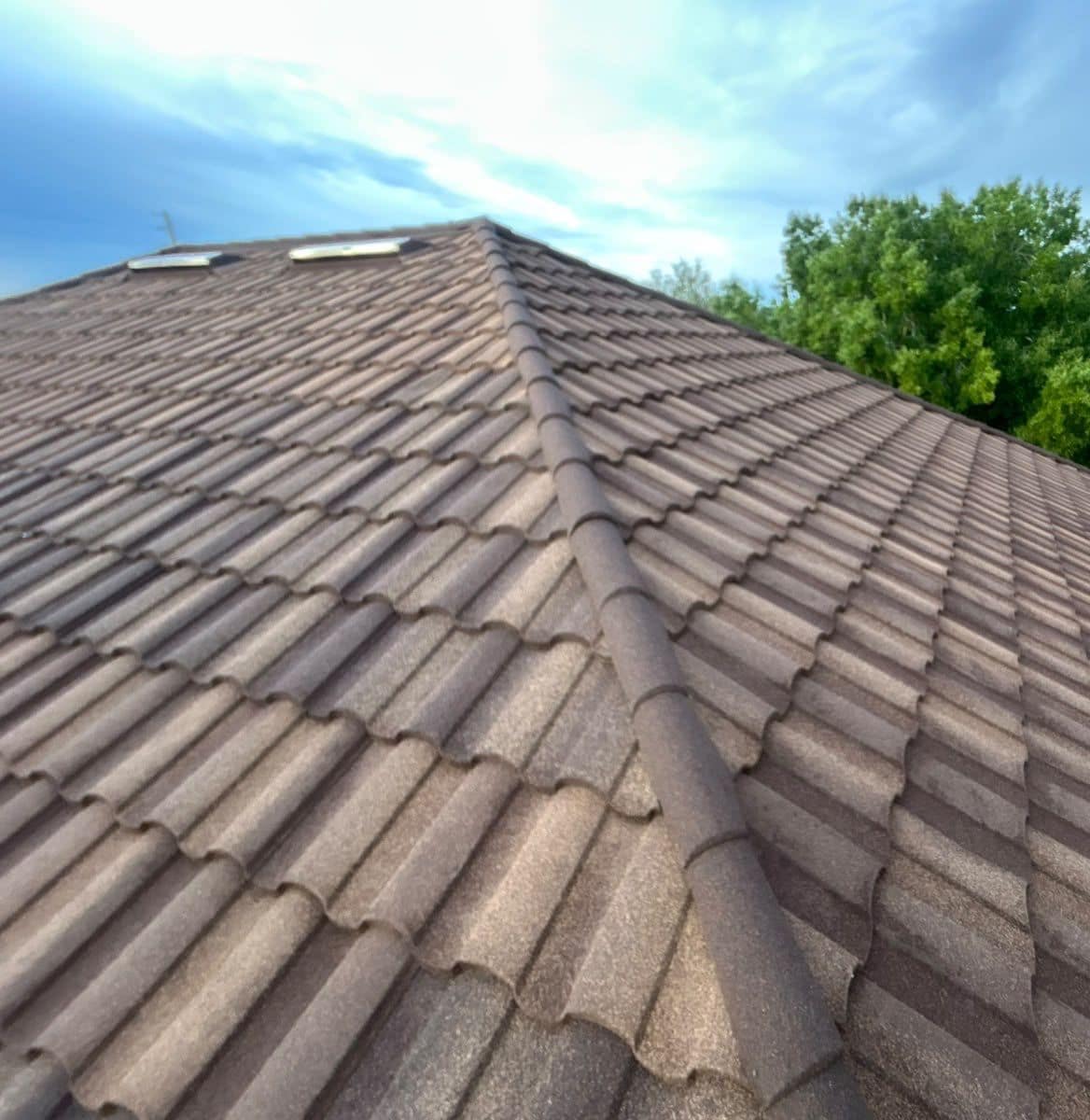 Rounded metal caps climbing a hip toward two low roof vents near the peak