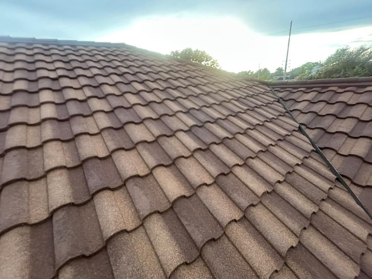 Narrow dark metal valley where two slopes of brown and tan metal tile meet