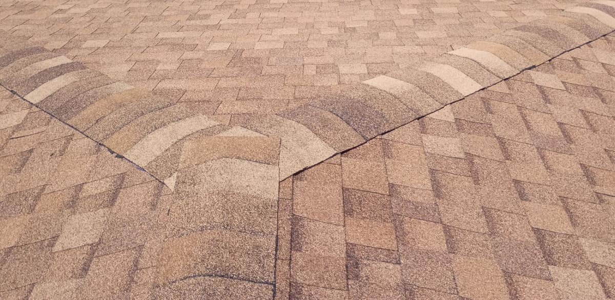 Close view of tan, cream and brown cap shingles where two hips meet a ridge
