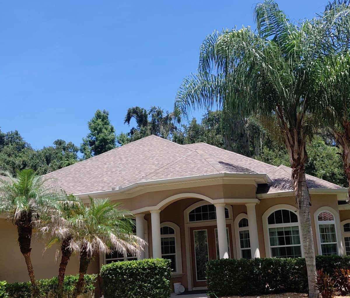 Palm Coast stucco home with an arched porch and white columns under a new Natural Timber roof