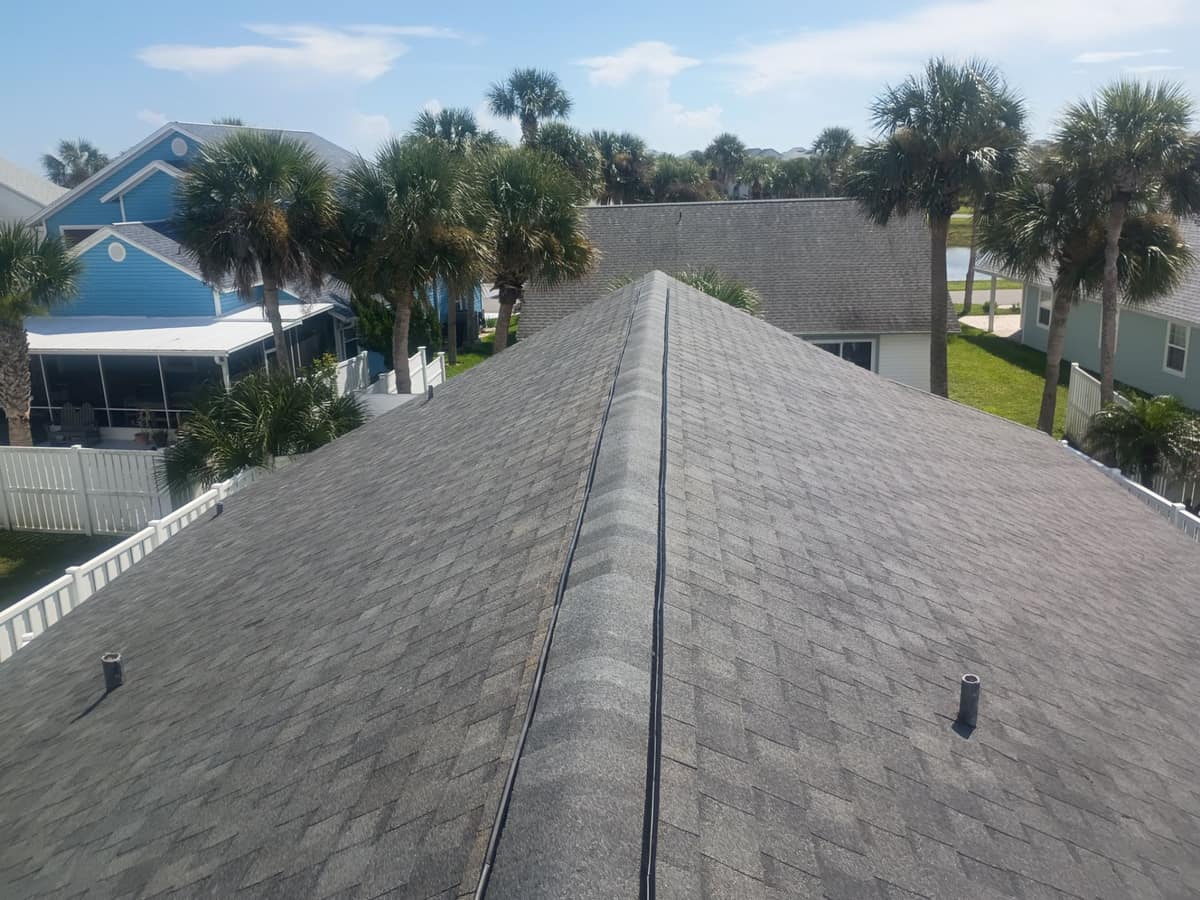 Palm Coast roof in Shadow Grey seen along the main ridge, with palms and screened porches beyond