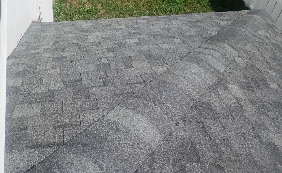 Hip on a lower roof section beside a white wall, with charcoal and gray tabs