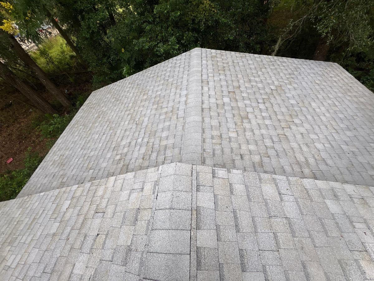 Looking down on a Webster hip roof in light gray TAMKO Titan XT shingles, woods all around